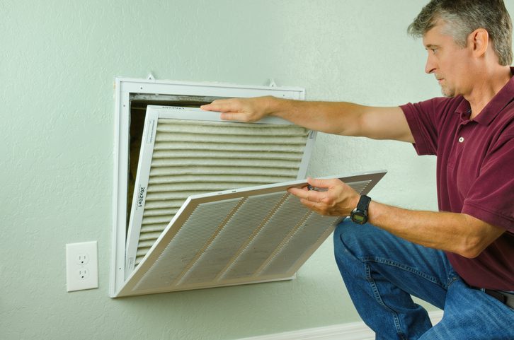 Home owner replacing air filter on air conditioner